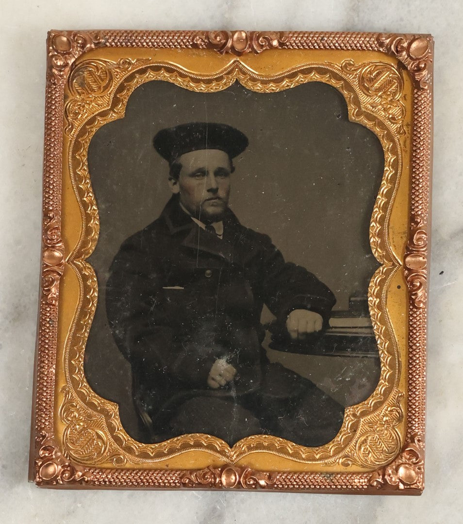 Lot 114 - Antique Matted Tintype Photograph Behind Glass Of Young Man In Peacoat With Beret Hat, Books On Table