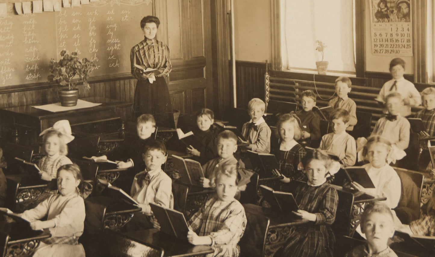 Lot 060 - Antique Boarded Photograph Of The Interior Of A 2Nd Grade Classroom With School Children, Teacher Holding Books,