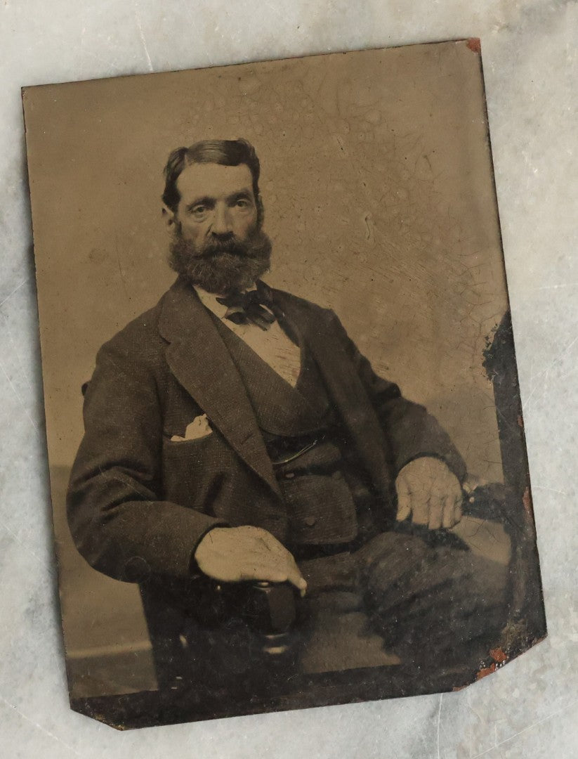 Lot 075 - Pair Of Tintype Photographs Of An Old Man With Large Hands And Unusual Face And Big Bushy Beard, And Stern Woman With Large Neck Bow
