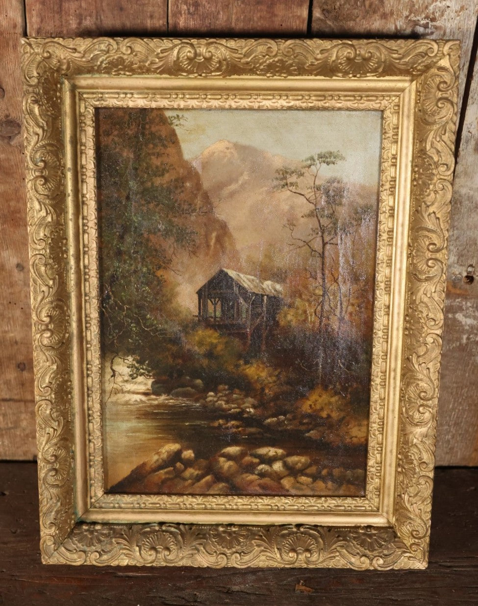 Antique Oil On Canvas Painting Of A Cabin In The Woods At The Base Of A Mount And Edge Of A Creek With Trees In Ornate Gilt Frame