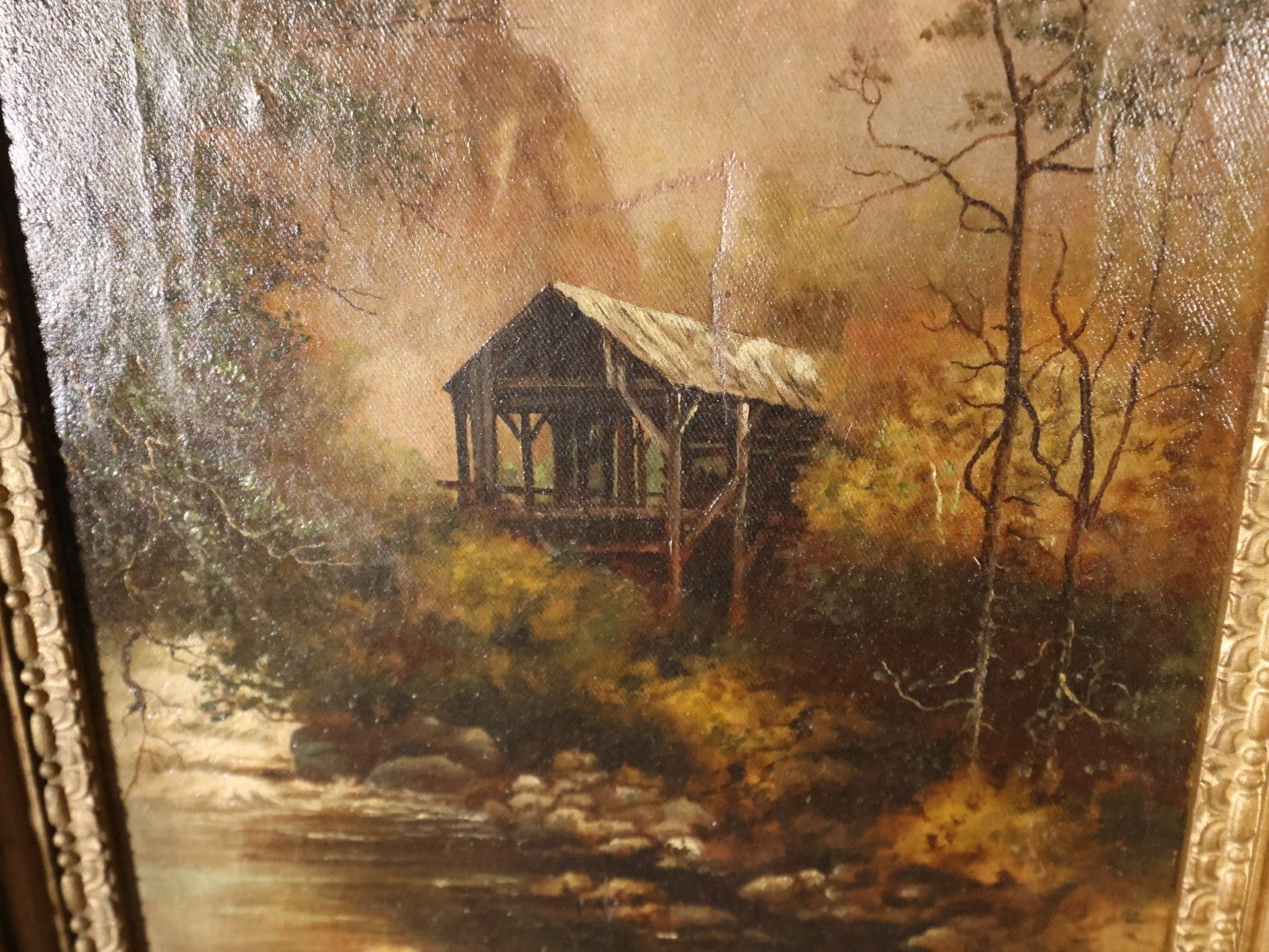 Antique Oil On Canvas Painting Of A Cabin In The Woods At The Base Of A Mount And Edge Of A Creek With Trees In Ornate Gilt Frame