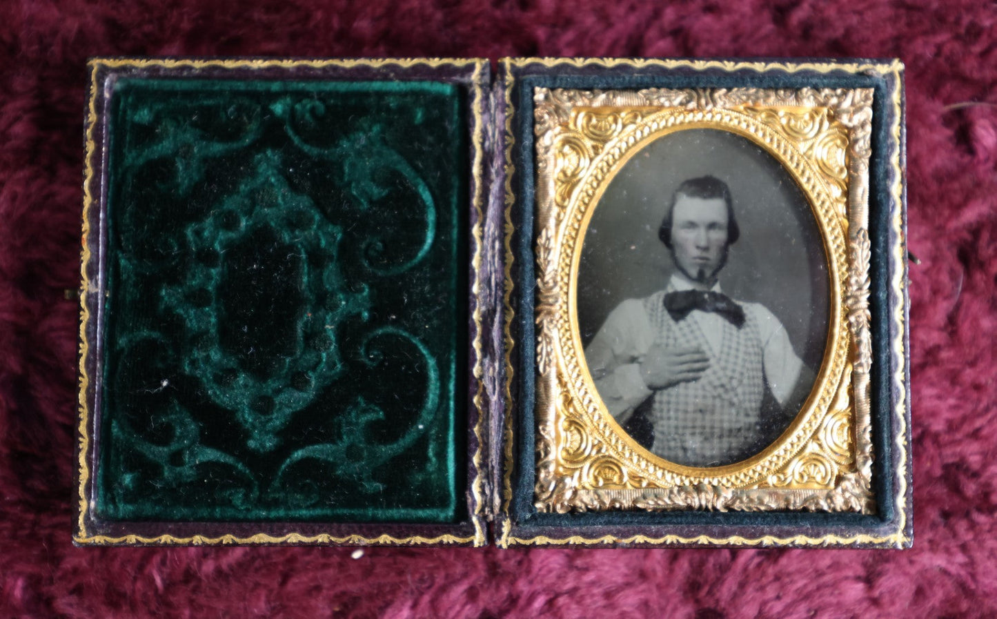 Lot 042 - Antique 9Th Plate Ruby Ambrotype Photograph Of Young Man, Large Bowtie, Hand On Chest, In Full Leatherette Case With Beautiful Green Pillow