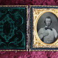 Lot 042 - Antique 9th Plate Ruby Ambrotype Photograph Of Young Man, Large Bowtie, Hand On Chest, In Full Leatherette Case With Beautiful Green Pillow