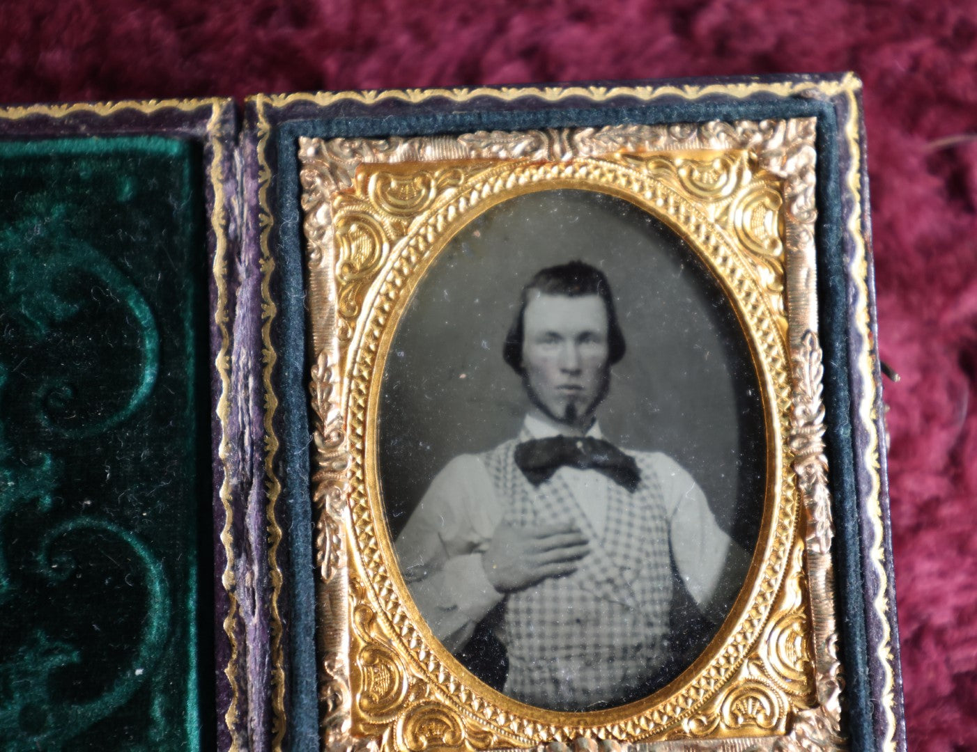 Lot 042 - Antique 9Th Plate Ruby Ambrotype Photograph Of Young Man, Large Bowtie, Hand On Chest, In Full Leatherette Case With Beautiful Green Pillow