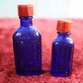 Lot 080 - Grouping Of Two Small Blue Poison Bottles With Red Caps