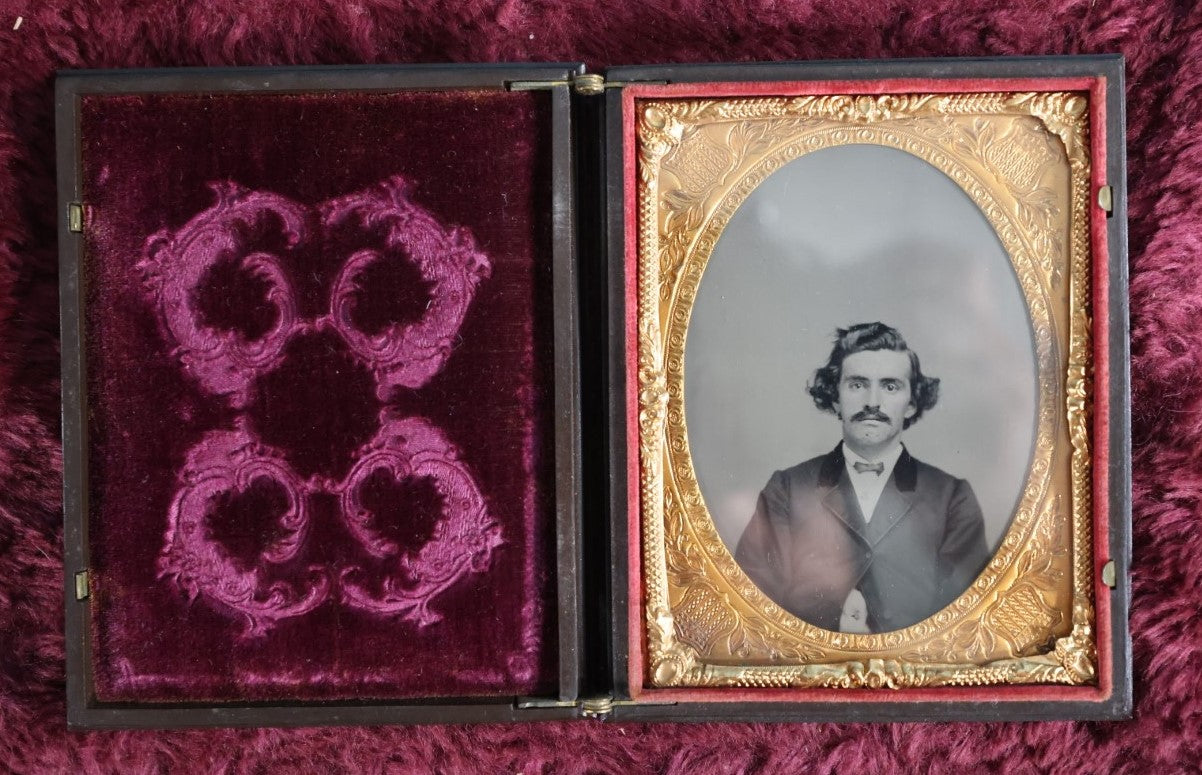 Lot 161 - Quarter Plate Ambrotype Of Handsom Young Man With Interesting Look, Mustache, Unusual Headroom Framing, Near Perfect Condition Large Size Thermoplastic Case With Lay Flat Hinge, Patriotic Shield Brass Mat