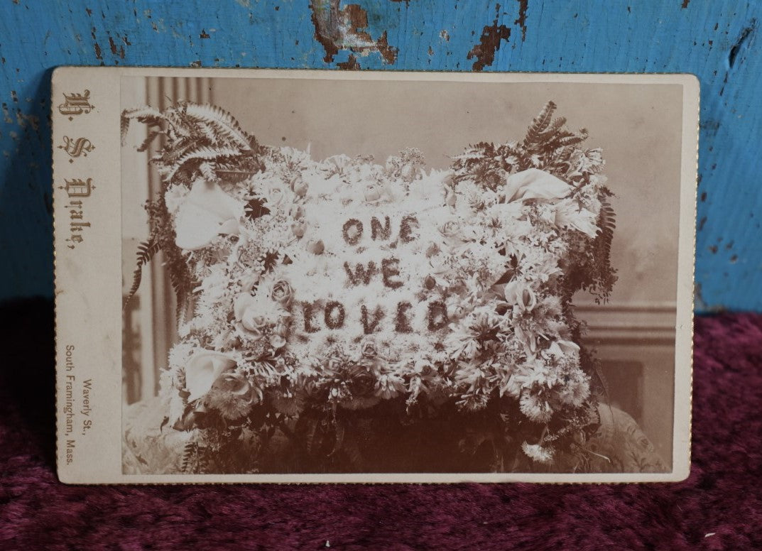 Lot 094 - Anitque Cabinet Card Photograph Of Funeral Flowers Memorial "One We Loved" In Pillow Shape, Photographed By H.S. Drake, South Framingham, Massachusetts