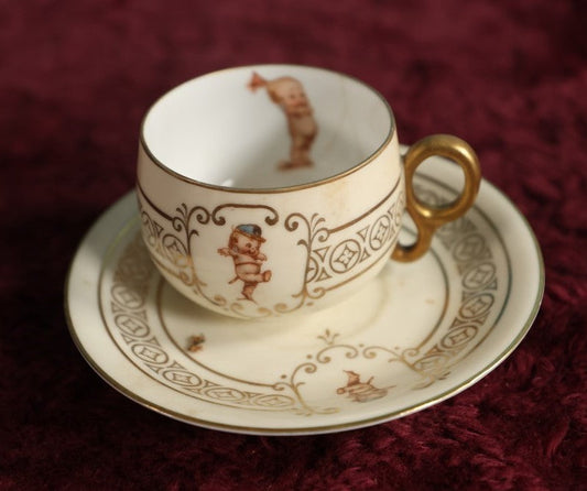 Lot 062 - Antique Royal Munich Kewpie Decorated Tea Cup And Saucer, Rose O'Neill, Marked Bavaria, Note Hairlines In Teacup