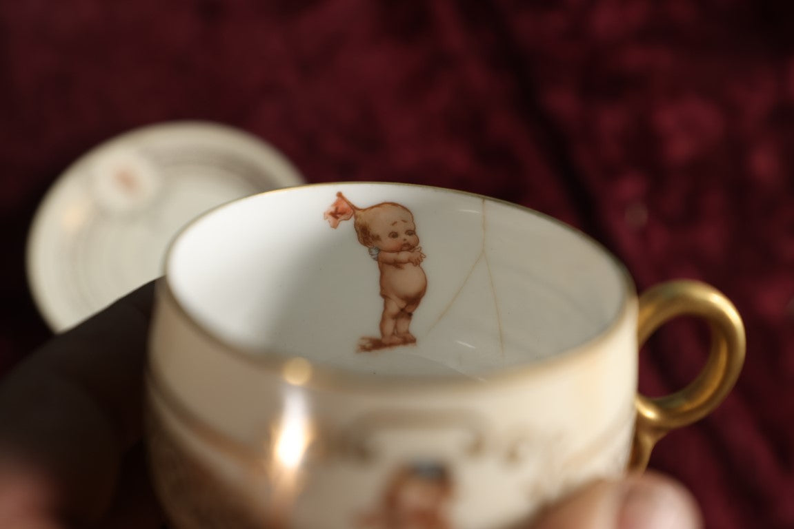 Lot 062 - Antique Royal Munich Kewpie Decorated Tea Cup And Saucer, Rose O'Neill, Marked Bavaria, Note Hairlines In Teacup