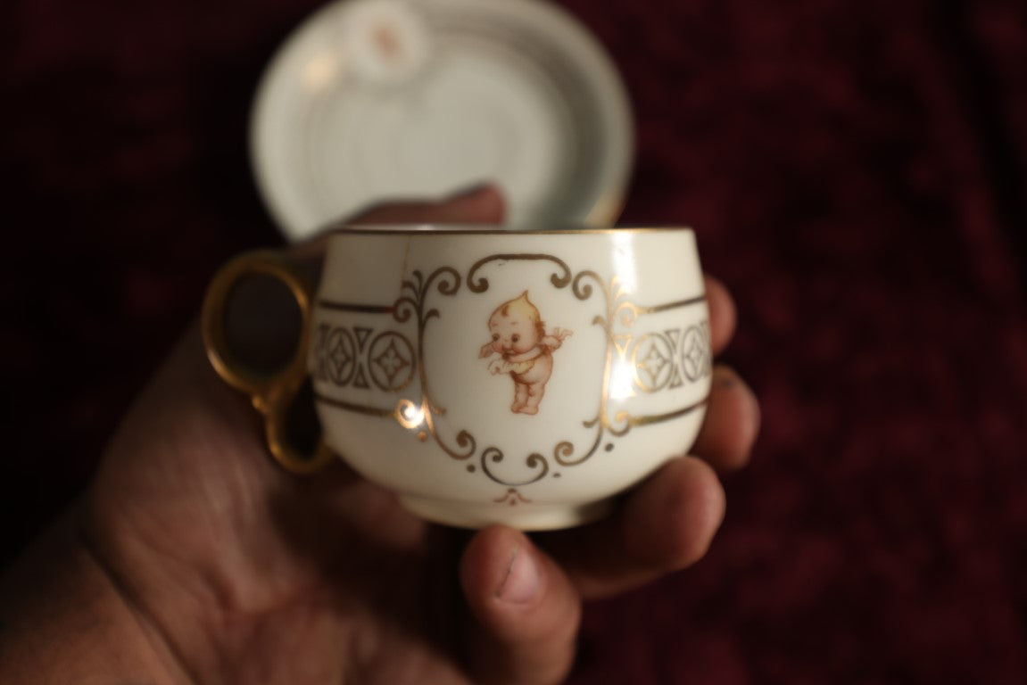 Lot 062 - Antique Royal Munich Kewpie Decorated Tea Cup And Saucer, Rose O'Neill, Marked Bavaria, Note Hairlines In Teacup