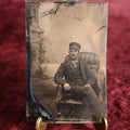 Lot 105 - Tintype - Man In Cap Sitting In Chair With Legs Crossed, Relaxed Posture, Leather Chair