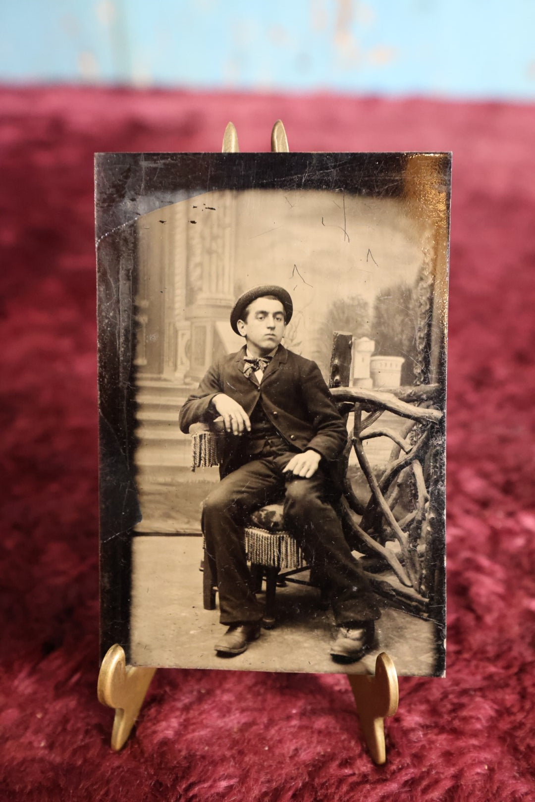 Lot 106 - Tintype - Man Sitting In Chair, Leaning On Elbow, In Hat, With Branch Gate Behind Him