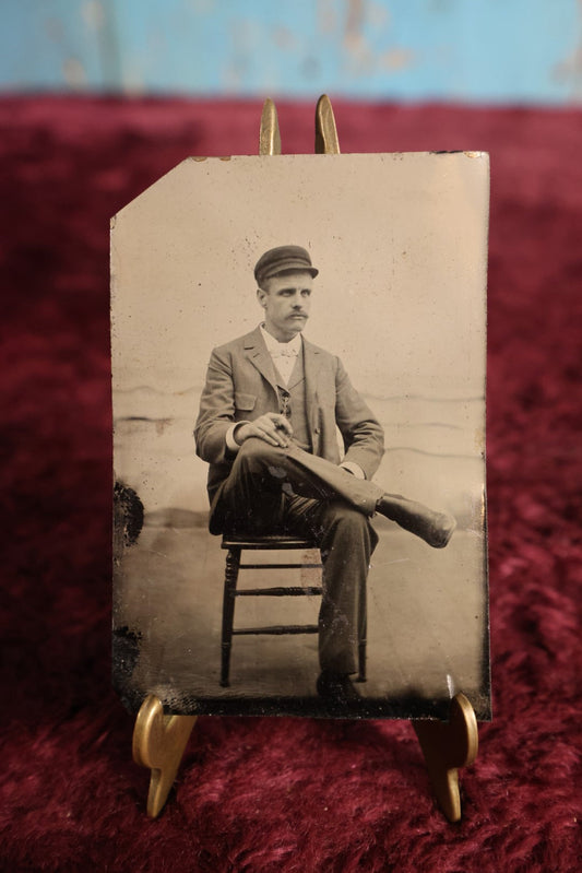 Lot 111 - Tintype - Young Man Sitting With Legs Crossed, Wearing Cap, Smoking Cigar