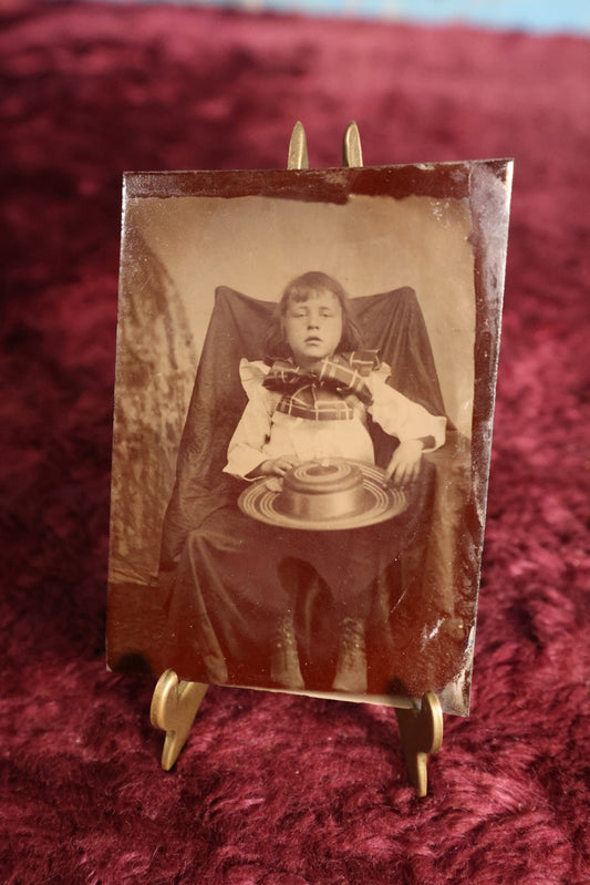 Lot 121 - Tintype - Upset Looking Young Girl Sitting In Chair With Wide Hat In Her Lap, Large Bow