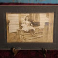 Lot 133 - Small Boarded Photo - Little Girl Sitting On Stoop Holding Two Dolls