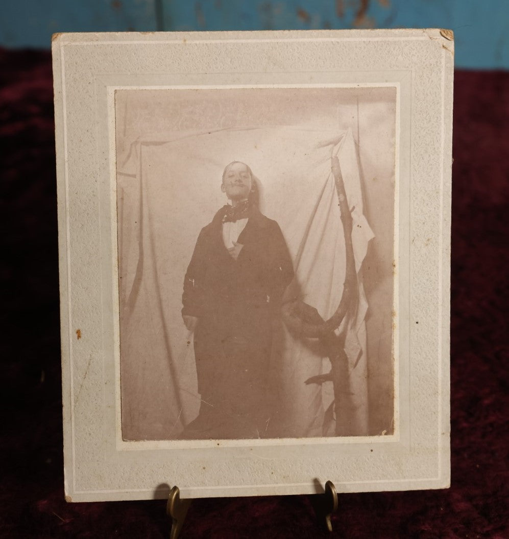 Lot 138 - Small Boarded Photo - Young Man In Costume With Fake Mustache Smoking Cigarette, Against White Sheet, Tree Branch