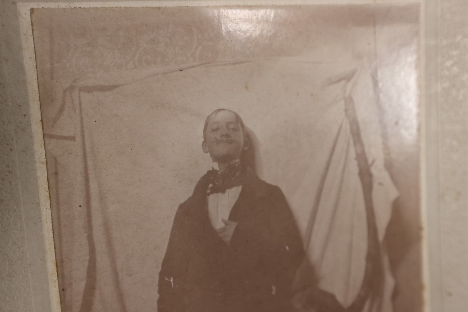 Lot 138 - Small Boarded Photo - Young Man In Costume With Fake Mustache Smoking Cigarette, Against White Sheet, Tree Branch