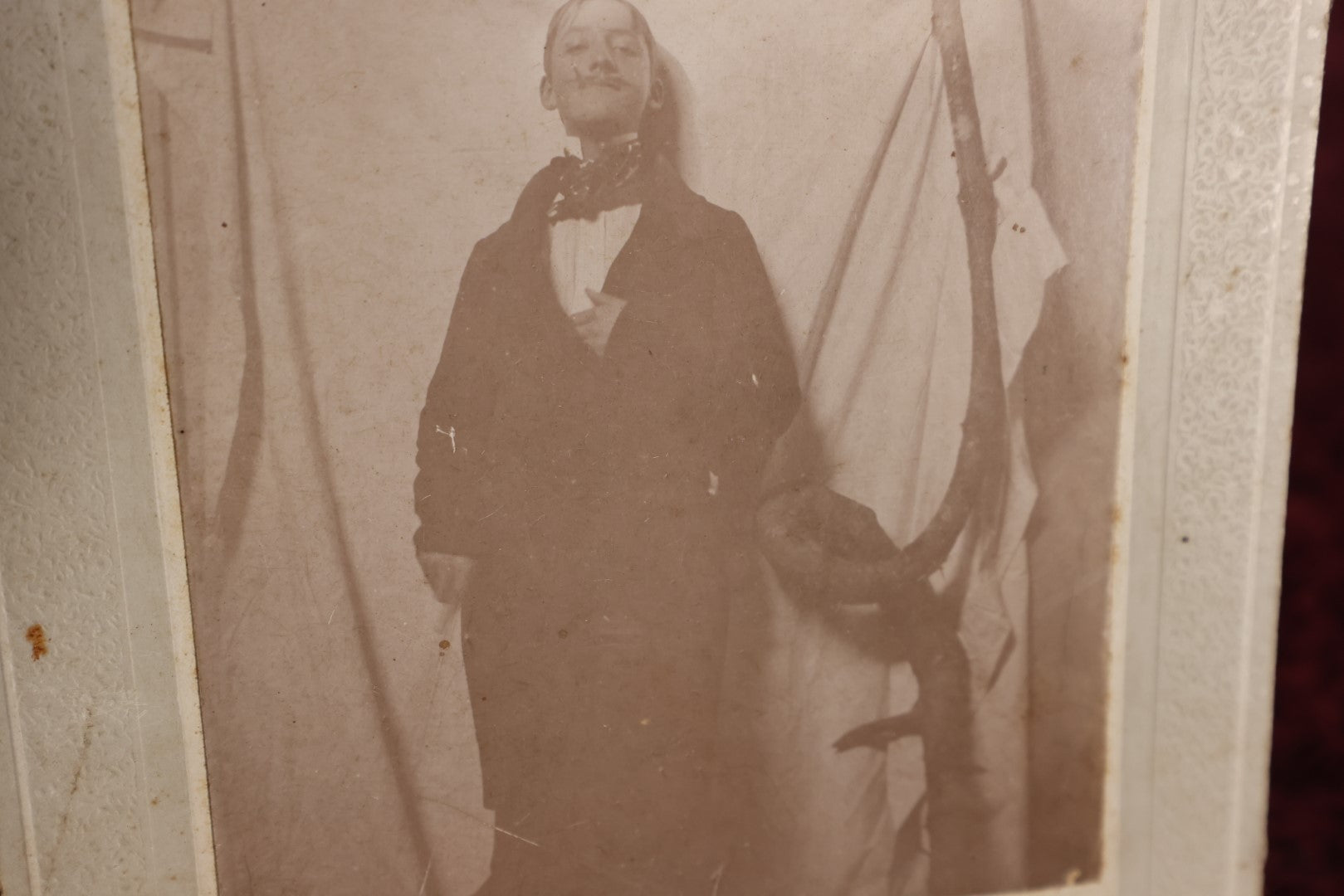 Lot 138 - Small Boarded Photo - Young Man In Costume With Fake Mustache Smoking Cigarette, Against White Sheet, Tree Branch