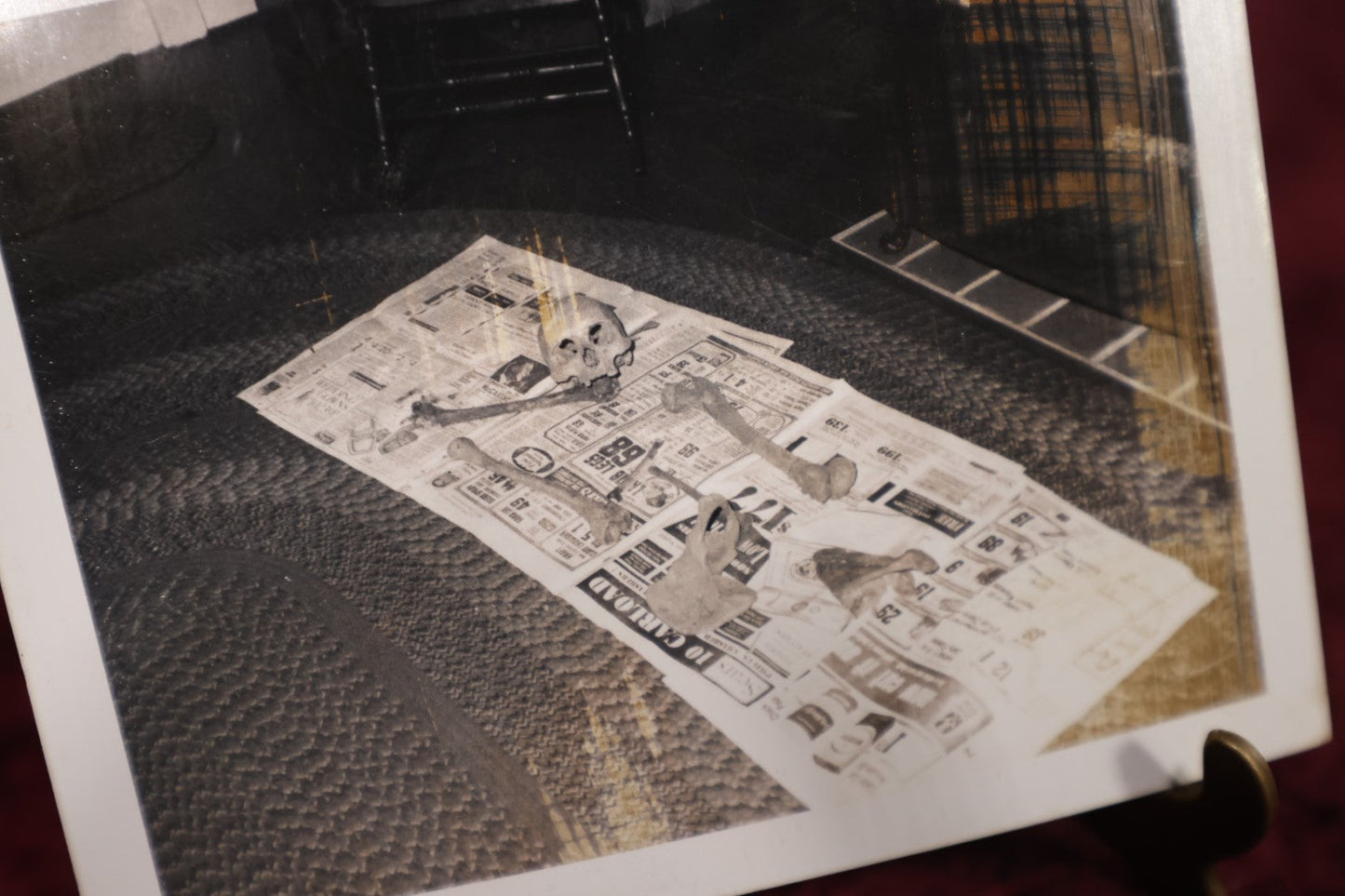 Lot 016 - Unusual 20th Century Black And White Snapshot Photo of Human Remains, Skeleton, Skull, Bones Laid Out On Newspaper In Front of A Fireplace