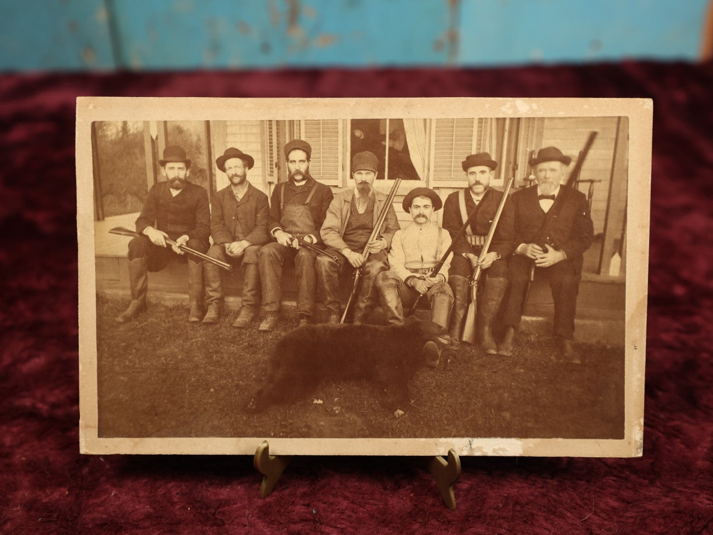 Lot 015 - Antique Boarded Photo Of Seven Men Hunters With Shotguns And Dead Bear Cub, Hunting Interest, Note Man In Window, Back Marked Ella E. Plummer