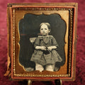 Lot 021 - Antique 1/6th Plate Daguerreotype Of Young Toddler Sitting, Looking Unsure Of Camera, Holding Something In Her Lap, In Half Case