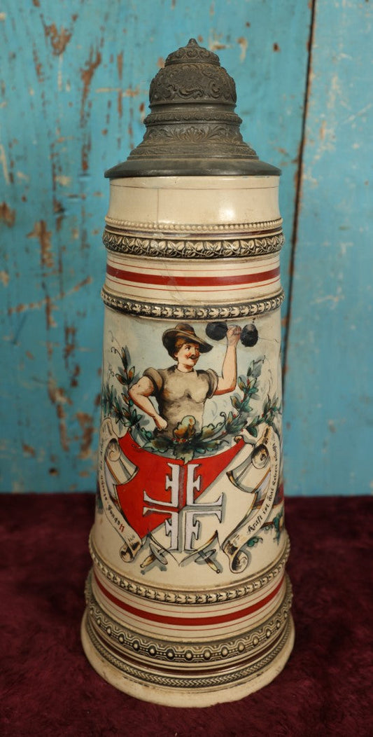 Lot 047 - Antique Hand Painted German Strong Man Stein With Weight Lifter, Metal Top, Two Liter, Note Heavy Damage, Repairs, Wear, Cracking