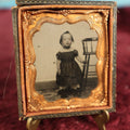 Lot 073 - Antique 1/6th Plate Ruby Ambrotype Of Young Girl Toddler Holding High Chair, Dark Off The Shoulders Dress, Heavy Wear To Case