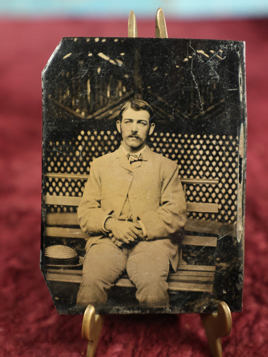 Lot 116 - Single Tintype Photo, Man Sitting On Park Bench With Hands In Lap, Hat By His Side