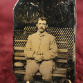 Lot 116 - Single Tintype Photo, Man Sitting On Park Bench With Hands In Lap, Hat By His Side