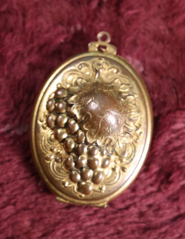 Lot 018 - Vintage Brass Locket With Grape Motif Containing Snapshot Photos Of A Young Boy And A Pretty Woman