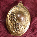 Lot 018 - Vintage Brass Locket With Grape Motif Containing Snapshot Photos Of A Young Boy And A Pretty Woman