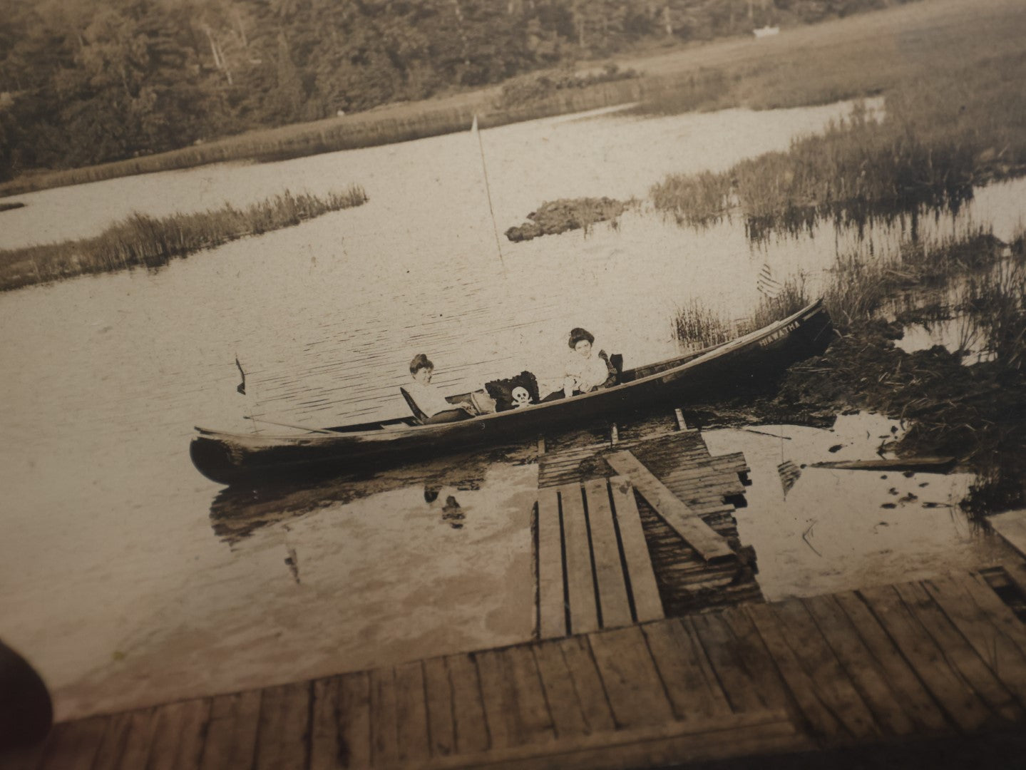 Lot 050 - Unusual Antique Framed Photo Of Two Women In A Canoe With A Skull And Crossbones / Jolly Roger Pillow, Boat Named Hiawatha, American Flag In Frame