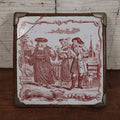 Lot 077 - Antique Painted Tile In Frame Trivet / Wall Hanger, Street Scene With Man, Baby, Pig, Dog, Church And Cemetery In Background, Note Severe Damage, Repairs