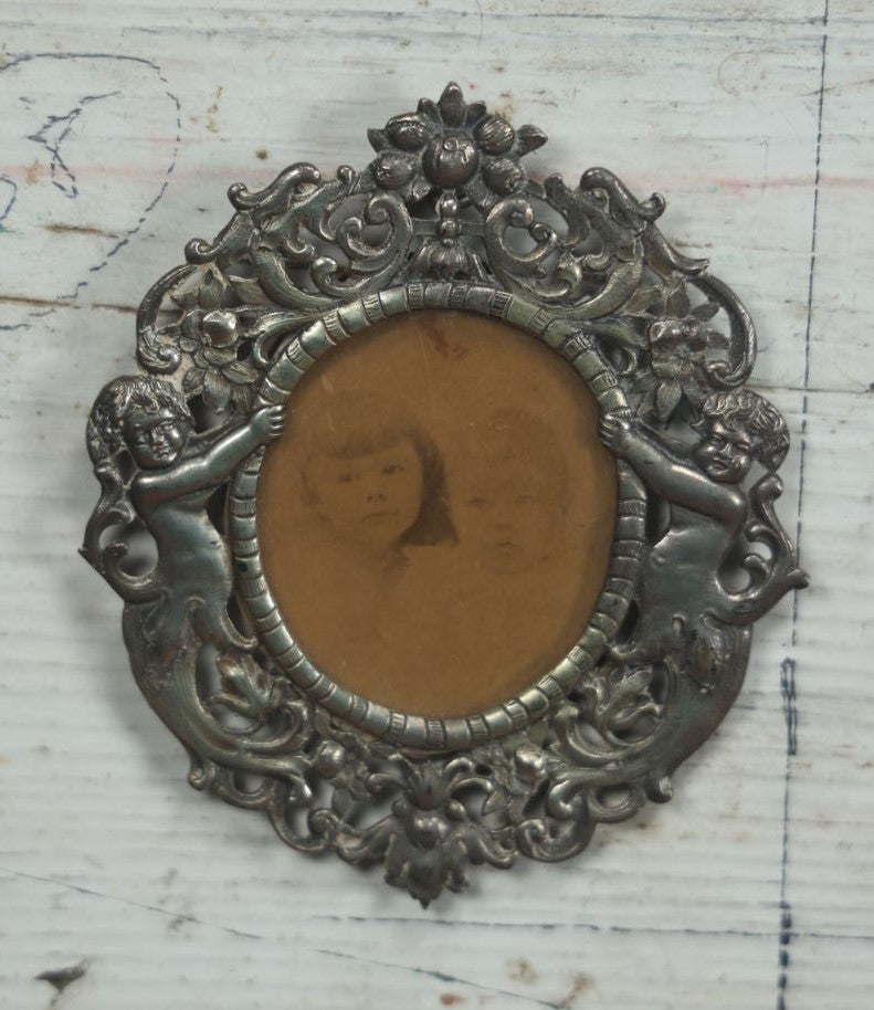 Lot 012 - Diminutive Antique Cast Silvertone Metal Frame With Cherubs On Sides, From Florence, Italy, By George W. Child, Containing An Identified Photo Of Lora F. Child And Donald Pratt, Circa 1895