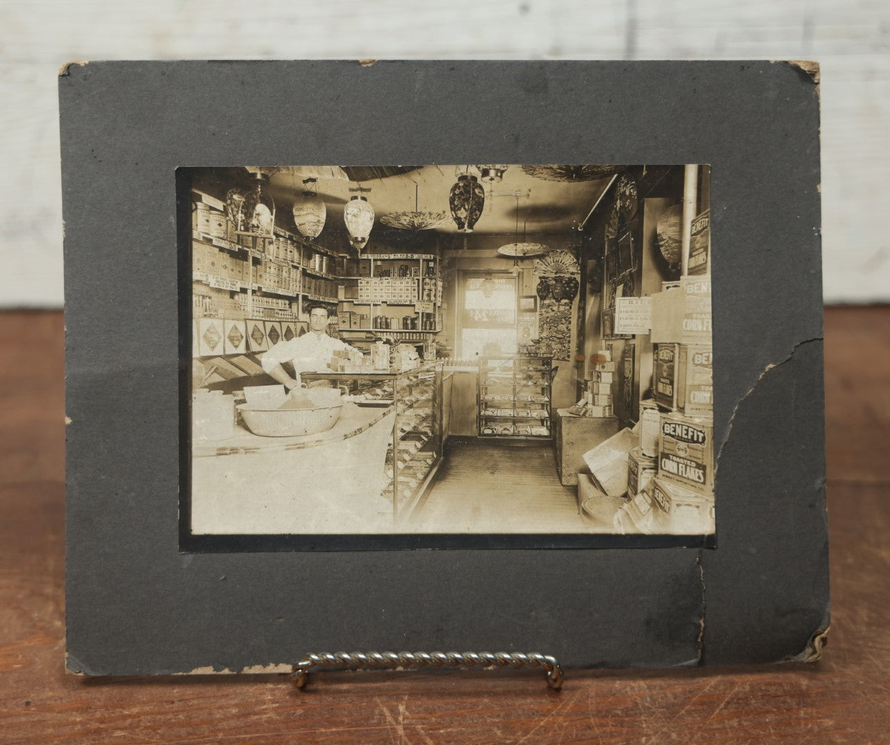 Lot 076 - Antique Boarded Occupational Photograph Of A Handsome Shopkeeper In A General Store, With Advertising, Chinese Lanterns With Tea Ads, And More, Note Bend In Corner