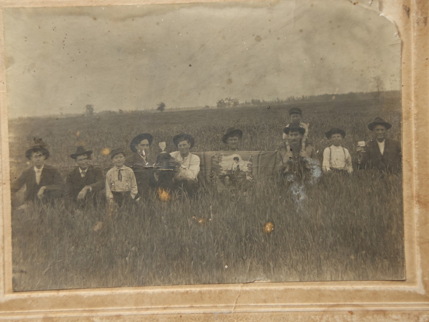 Lot 082 - Antique  Boarded Photograph Of A Group Of People In A Tall Grass Field, One Man Holding Pained Banner