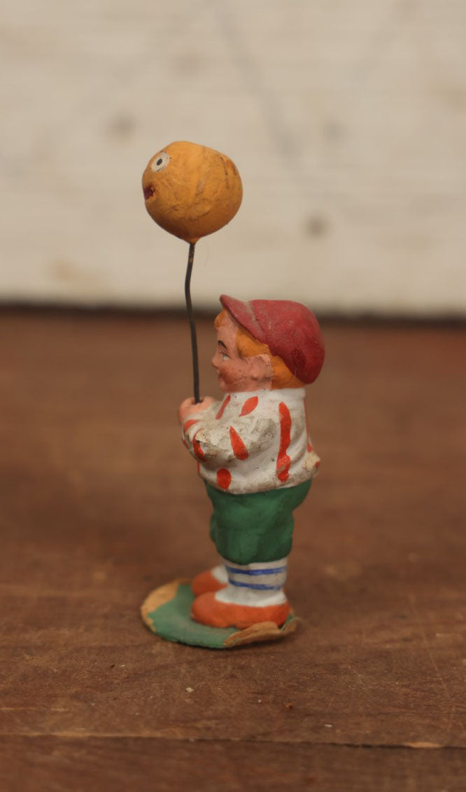 Lot 037 - Rare German Halloween Figurine, Papier Mache Or Bisque, Little Boy Holding Halloween Jack-O-Lantern J.O.L. Pumpkin Balloon