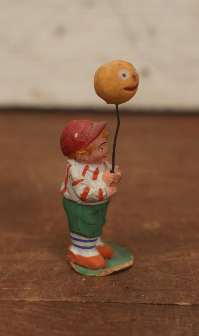 Lot 037 - Rare German Halloween Figurine, Papier Mache Or Bisque, Little Boy Holding Halloween Jack-O-Lantern J.O.L. Pumpkin Balloon