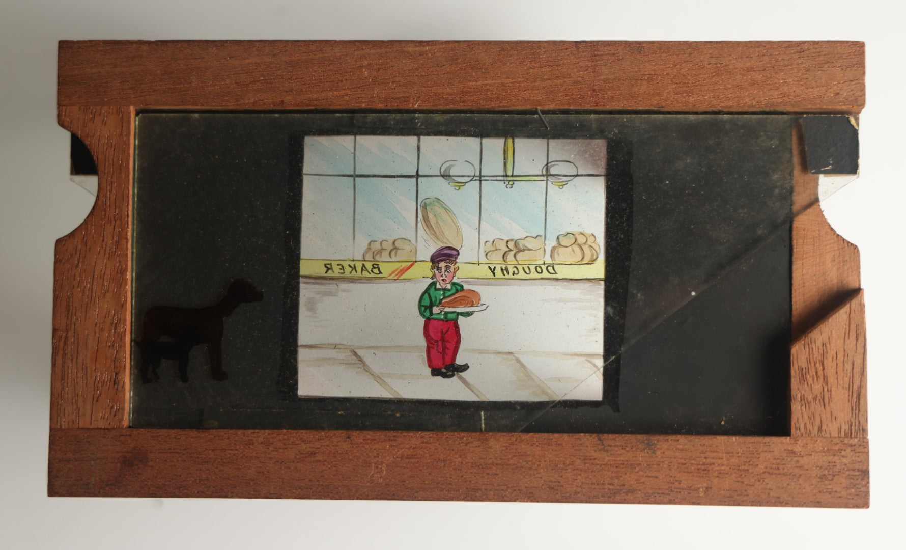 Lot 041 - Antique Hand Painted Animated Magic Lantern Motion Slide, Young Boy With Chicken Outside Bakery Surrounded By Dogs, Dogs Slide In From Both Sides