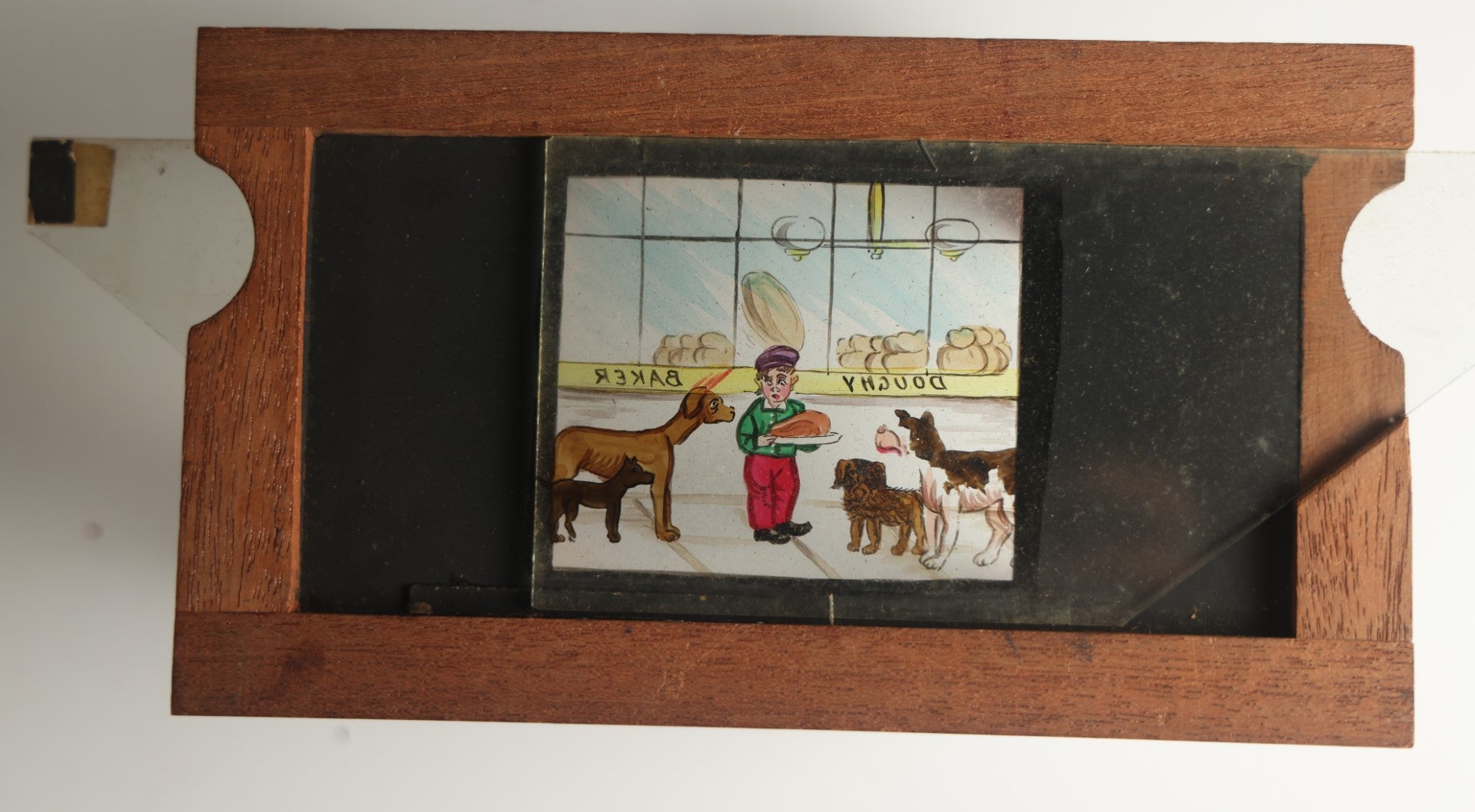 Lot 041 - Antique Hand Painted Animated Magic Lantern Motion Slide, Young Boy With Chicken Outside Bakery Surrounded By Dogs, Dogs Slide In From Both Sides