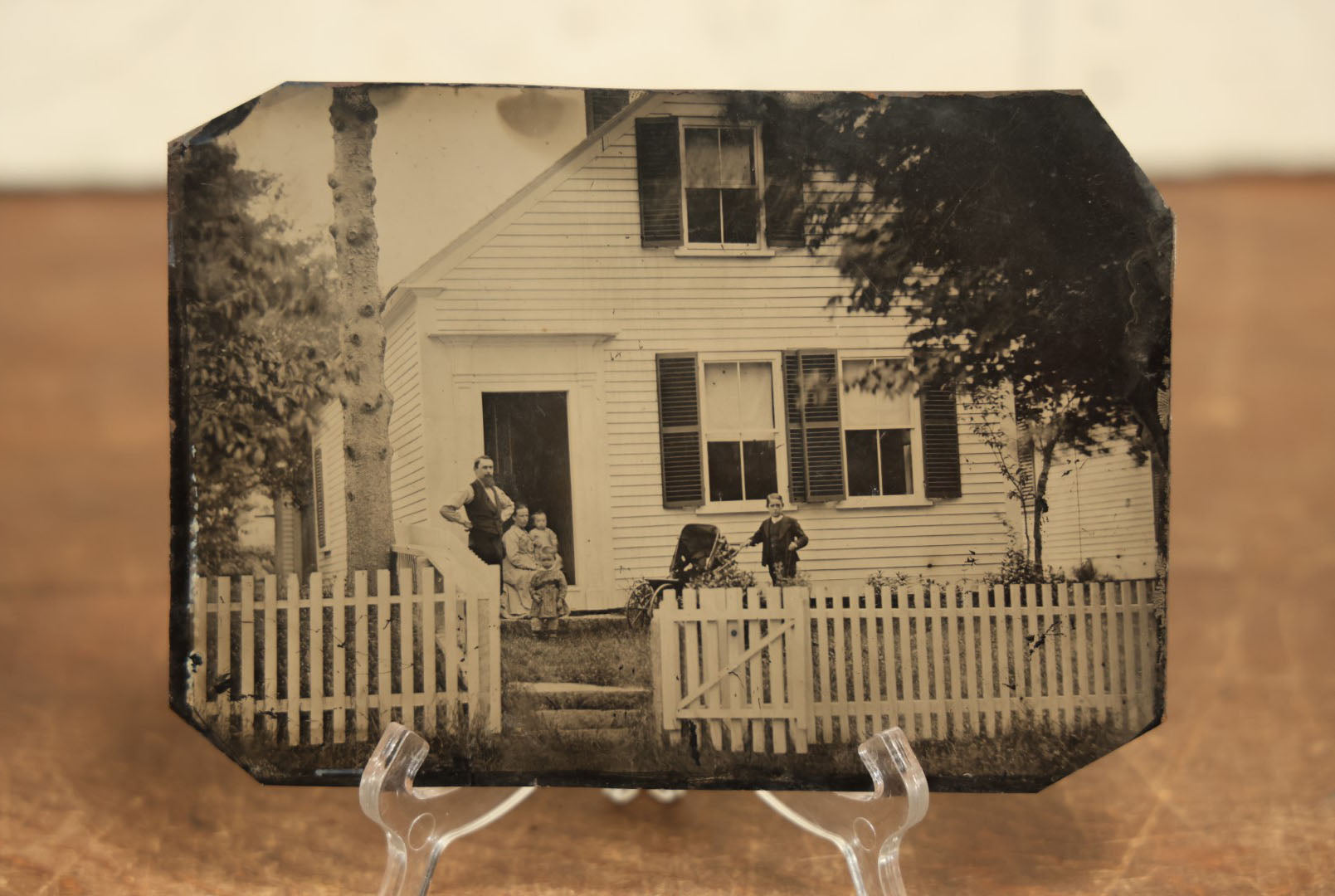 Lot 012 - Large Plate Exterior Tintype Of A Family Outside Of Their Home, Two Adults And Three Children, With White Picket Fence, 6-7/8" x 4-7/8"