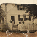 Lot 012 - Large Plate Exterior Tintype Of A Family Outside Of Their Home, Two Adults And Three Children, With White Picket Fence, 6-7/8" X 4-7/8"