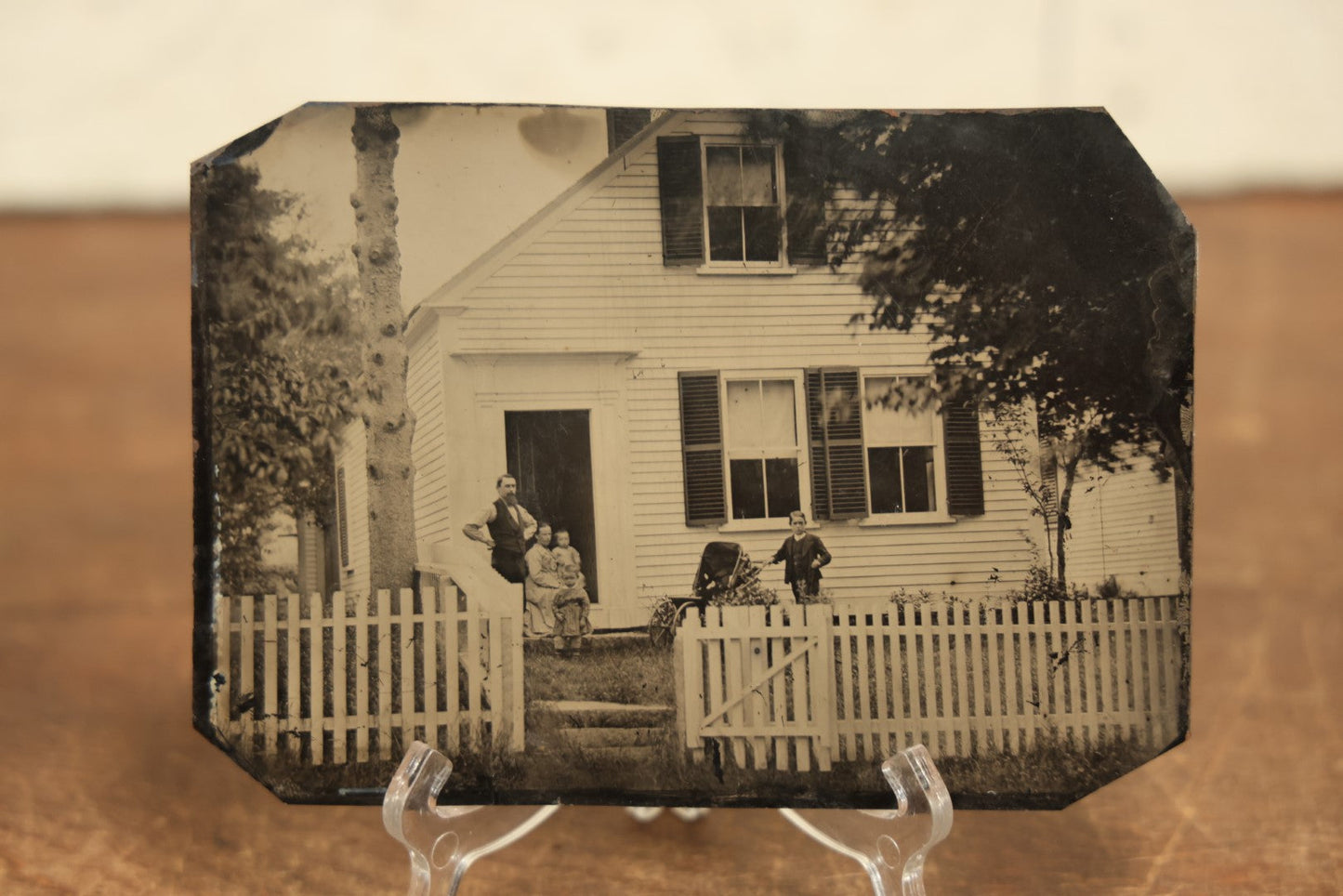 Lot 012 - Large Plate Exterior Tintype Of A Family Outside Of Their Home, Two Adults And Three Children, With White Picket Fence, 6-7/8" x 4-7/8"