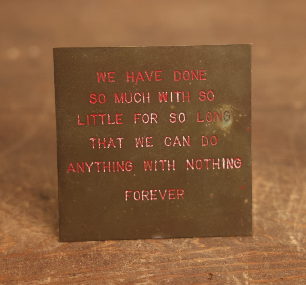 Lot 084 - Vintage Brass And Red Enamel Motto Plaque, "We Have Done So Much With So Little For So Long That We Can Do Anything With Nothing Forever"