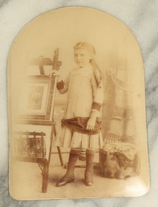 Lot 046 - Antique Unframed Bubble Glass Mounted Photo Of A Young Girl Leaning An Easel With Artwork, Identified As Emily Babb