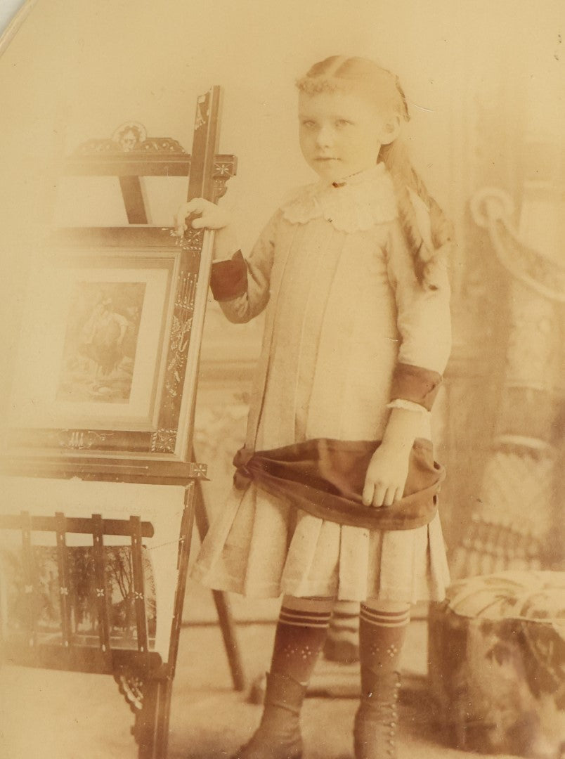 Lot 046 - Antique Unframed Bubble Glass Mounted Photo Of A Young Girl Leaning An Easel With Artwork, Identified As Emily Babb