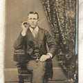 Lot 096 - Single Antique Tintype Photograph, Middle Aged Man Smoking A Cigar, With Watch Chain, Crossed Legs, Black Bow On Jacket