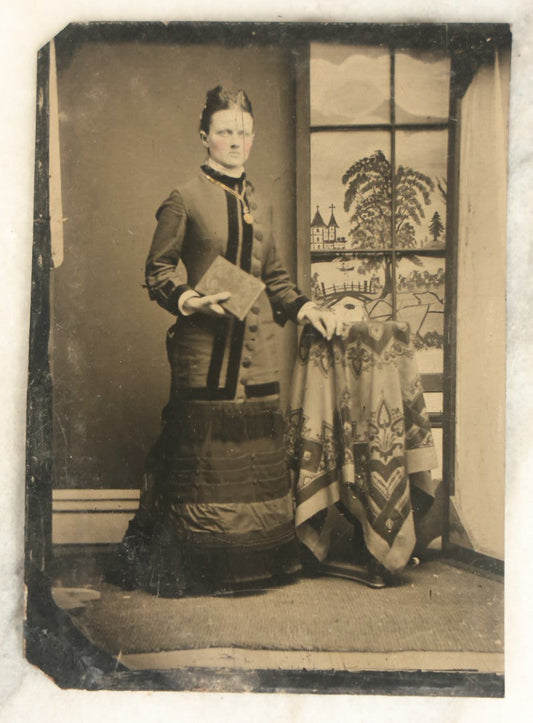 Lot 099 - Single Antique Tintype Photograph, Woman Standing In Front Of Faux Window With Country Scene, Holding Book