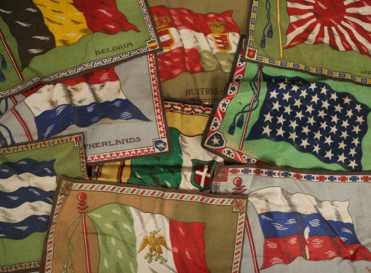 Lot 039 - Grouping Of Ten Antique Tobacco Felt Flags, Including Japan, 2 x Russia, Italy, Mexico, Cuba, Belgium, Netherlands, Austria-Hungary, And The Union Jack, Various Wear.