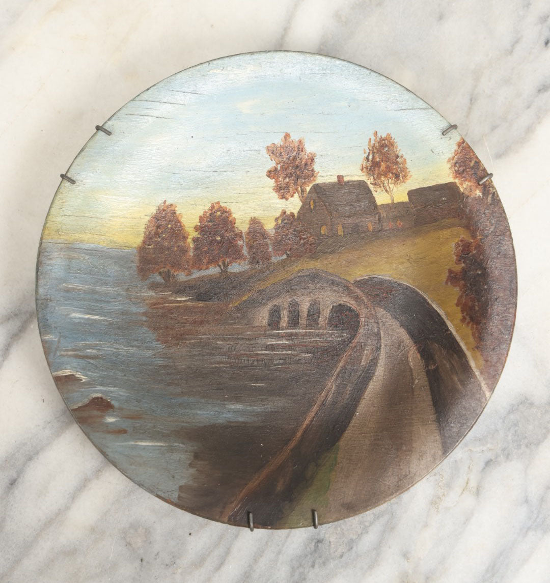 Lot 039 - Antique Hand Painted Wooden Plate, Landscape Scene With A Bridge Over A River, Foliage, With Plate Hanger